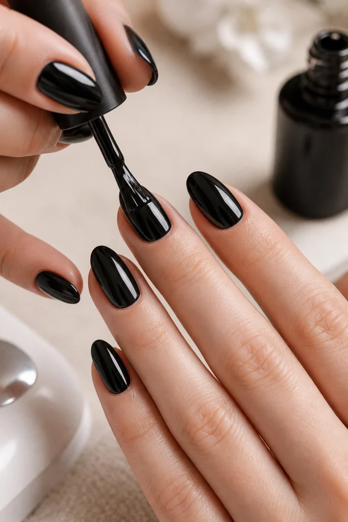 Applying black gel polish to almond shaped nails