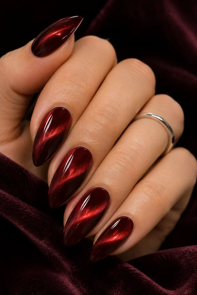 Deep cherry cola cat-eye nails with a reflective ruby magnetic shimmer.