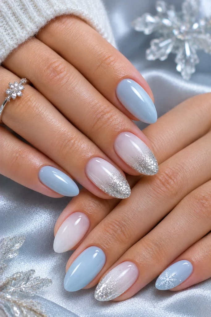 Alt text: Icy blue Christmas nails with silver glitter and a delicate snowflake.