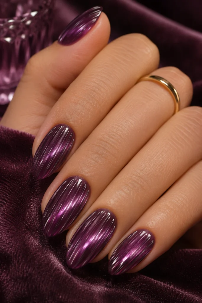 Deep plum cat-eye ribbed glass nails with raised crystal-like lines.